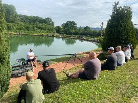John leading a group coaching session beside a lake